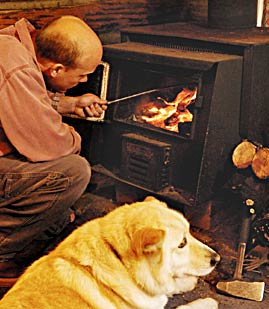 A man and his dog enjoy a crackling fireplace