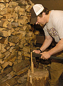 Man splitting firewood for more efficient drying.